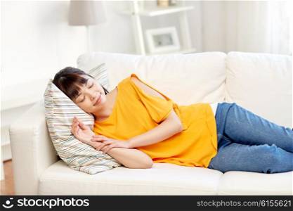 rest, relax and people concept - happy asian teenage girl or young woman sleeping on sofa at home