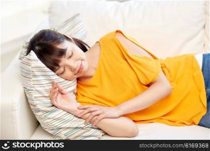 rest, relax and people concept - happy asian teenage girl or young woman sleeping on sofa at home