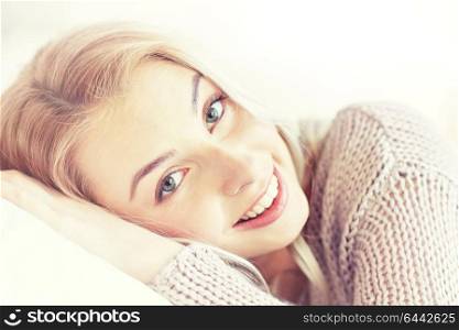 rest, relax and people concept - smiling young woman or teen girl lying on pillow at home. young woman or teen girl lying on pillow at home