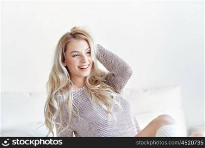 rest, sleeping, comfort and people concept - happy young woman stretching in bed at home bedroom