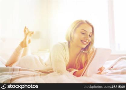 rest, sleeping, comfort and people concept - happy young woman with pen and notebook writing in bed at home bedroom