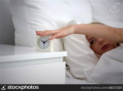 rest, sleeping, time and people concept - close up of young woman switching off alarm clock in bed at home bedroom