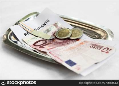 Restaurant bill and money on matal tray