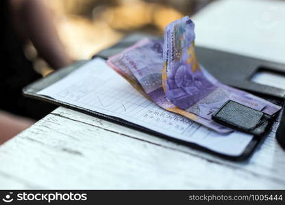 Restaurant bill with money on payment tray on the table, money is rupiah colors. Restaurant bill with money on payment tray on the table, money is rupiah