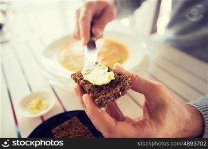 restaurant, couple and holiday concept - close up of hands applying and spreading butter to bread