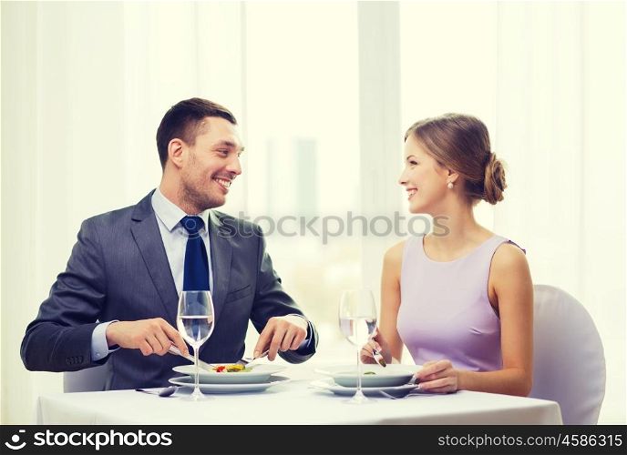 restaurant, couple and holiday concept - smiling couple eating appetizers at restaurant