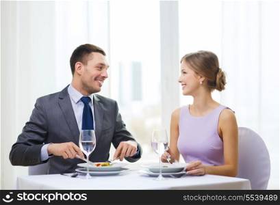 restaurant, couple and holiday concept - smiling couple eating appetizers at restaurant