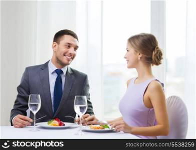 restaurant, couple and holiday concept - smiling couple eating main course at restaurant