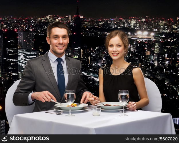 restaurant, couple and holiday concept - smiling couple eating main course at restaurant