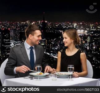 restaurant, couple and holiday concept - smiling couple eating main course at restaurant