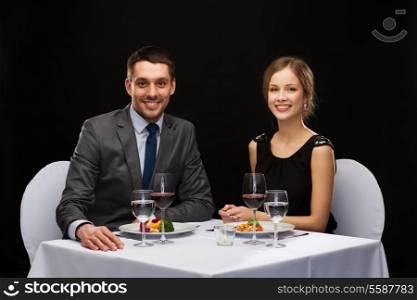 restaurant, couple and holiday concept - smiling couple eating main course with red wine at restaurant