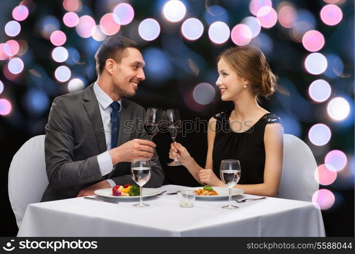 restaurant, couple and holiday concept - smiling couple eating main course with red wine at restaurant