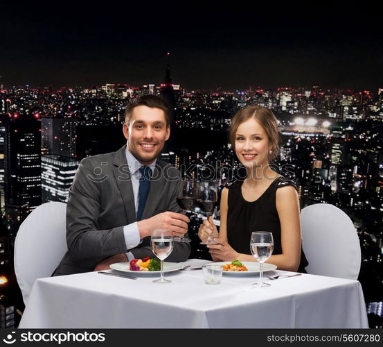 restaurant, couple and holiday concept - smiling couple eating main course with red wine at restaurant