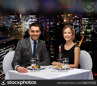 restaurant, couple and holiday concept - smiling couple eating main course with red wine at restaurant