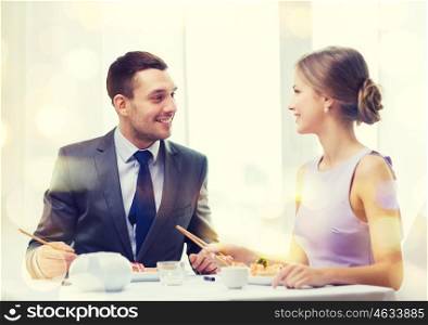 restaurant, couple and holiday concept - smiling couple eating sushi at restaurant