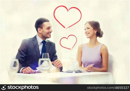 restaurant, couple and holiday concept - smiling couple looking at each other at restaurant