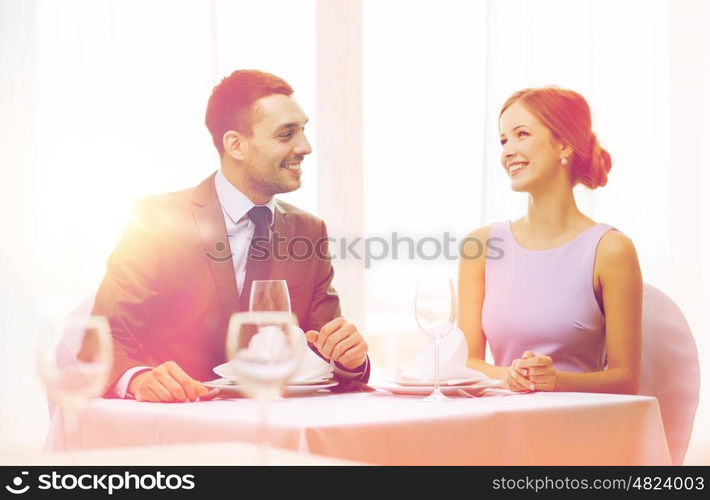 restaurant, couple and holiday concept - smiling couple looking at each other at restaurant