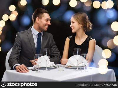 restaurant, couple and holiday concept - smiling couple looking at each other at restaurant