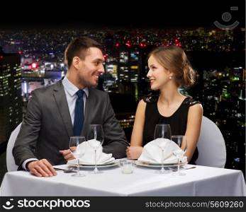 restaurant, couple and holiday concept - smiling couple looking at each other at restaurant