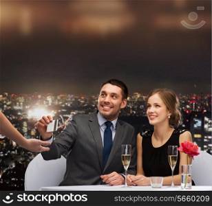 restaurant, couple and holiday concept - smiling couple paying for dinner with credit card at restaurant