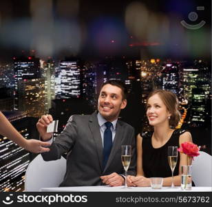 restaurant, couple and holiday concept - smiling couple paying for dinner with credit card at restaurant