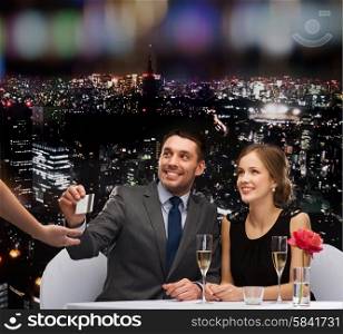 restaurant, couple and holiday concept - smiling couple paying for dinner with credit card at restaurant