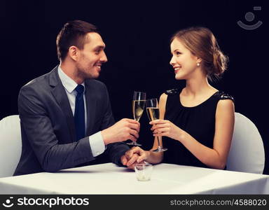 restaurant, couple and holiday concept - smiling couple with glass of champagne looking at each other at restaurant