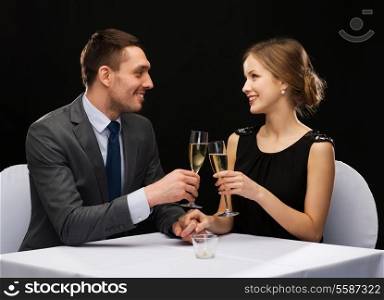 restaurant, couple and holiday concept - smiling couple with glass of champagne looking at each other at restaurant