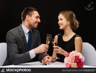 restaurant, couple and holiday concept - smiling couple with glass of champagne looking at each other at restaurant