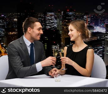 restaurant, couple and holiday concept - smiling couple with glass of champagne looking at each other at restaurant