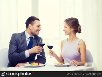 restaurant, couple and holiday concept - smiling couple with main course and red wine at restaurant