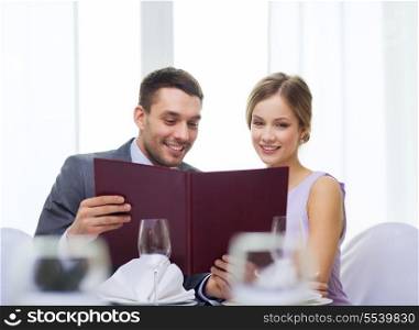 restaurant, couple and holiday concept - smiling couple with menu at restaurant