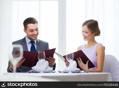 restaurant, couple and holiday concept - smiling couple with menus at restaurant