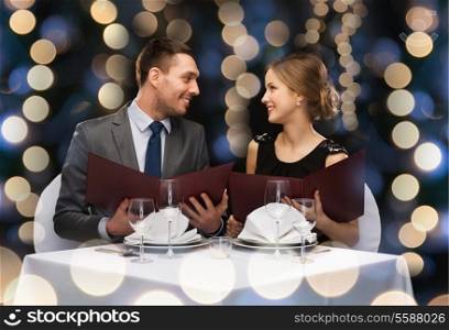 restaurant, couple and holiday concept - smiling couple with menus at restaurant