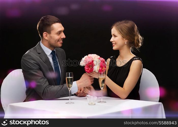 restaurant, couple and holiday concept - smiling man giving flower bouquet to woman at restaurant