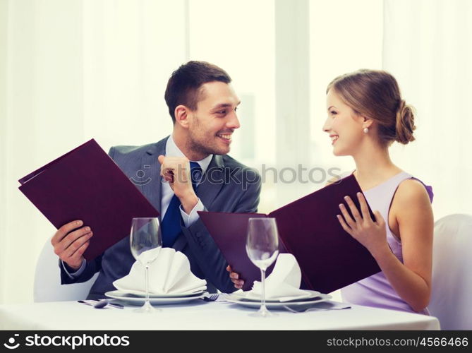 restaurant, couple and holiday concept - smiling man looking into girlfriends or wifes menu at restaurant