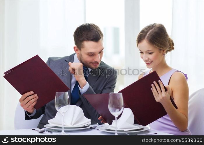 restaurant, couple and holiday concept - smiling man looking into girlfriends or wifes menu at restaurant
