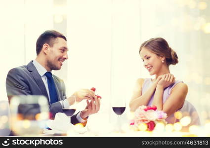 restaurant, couple and holiday concept - smiling man proposing to his girlfriend at restaurant