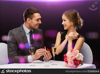 restaurant, couple and holiday concept - smiling man proposing to his girlfriend at restaurant