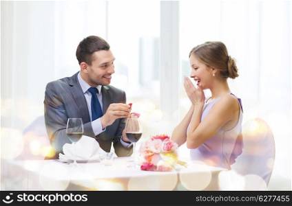 restaurant, couple and holiday concept - smiling man proposing to his girlfriend at restaurant