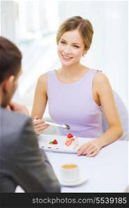 restaurant, couple and holiday concept - smiling woman eating dessert and looking at husband or boyfriend at restaurant