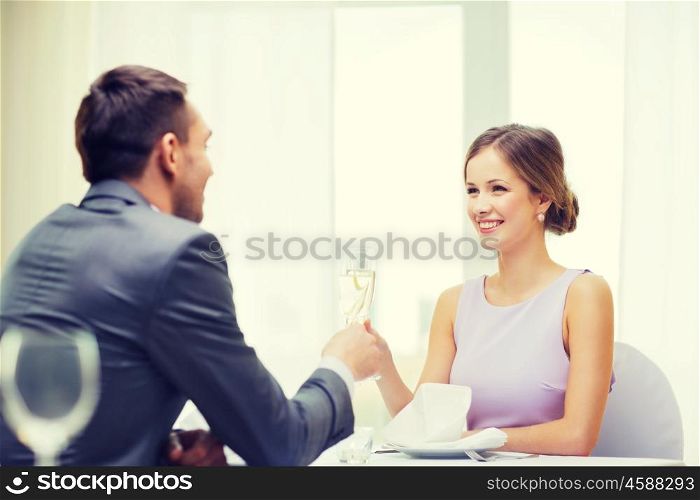 restaurant, couple and holiday concept - smiling woman with glass of champagne looking at husband or boyfriend at restaurant