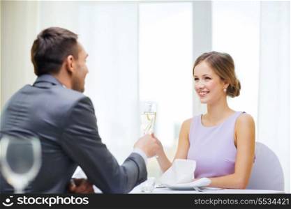 restaurant, couple and holiday concept - smiling woman with glass of champagne looking at husband or boyfriend at restaurant