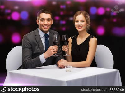 restaurant, couple and holiday concept - smiling young couple with glasses of red wine looking at each other at restaurant