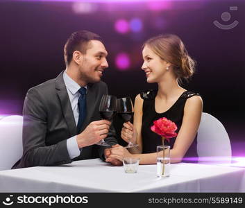 restaurant, couple and holiday concept - smiling young couple with glasses of red wine looking at each other at restaurant