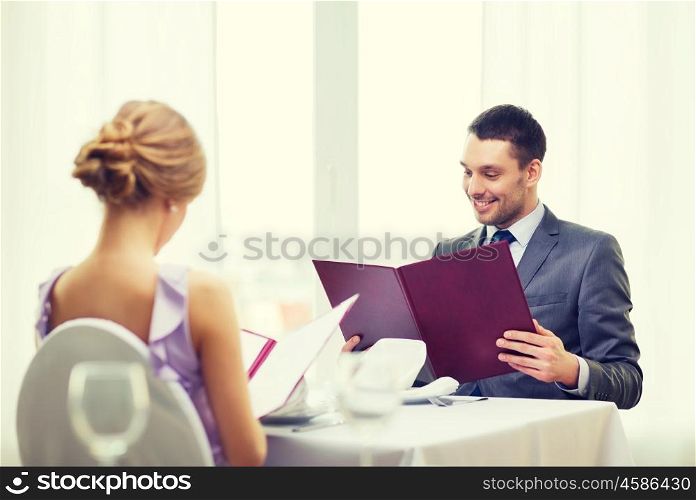 restaurant, couple and holiday concept - smiling young man looking at menu at restaurant