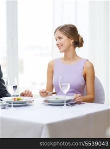 restaurant, couple and holiday concept - smiling young woman looking at husband or boyfriend while eating first course at restaurant