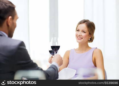 restaurant, couple and holiday concept - smiling young woman with glass of red wine looking at boyfriend or husband at restaurant