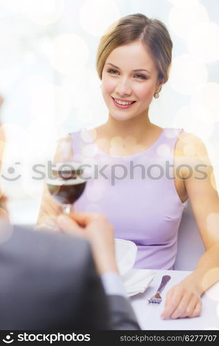 restaurant, couple and holiday concept - smiling young woman with glass of red wine looking at boyfriend or husband at restaurant