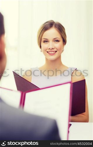 restaurant, couple and holiday concept - smiling young woman with menu at restaurant